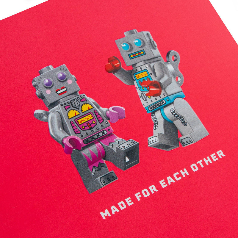 Two robot toys on a red background with text 'MADE FOR EACH OTHER'.