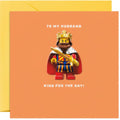 Greeting card with a king-themed design and text 'To my husband, king for the day!' on an orange background.