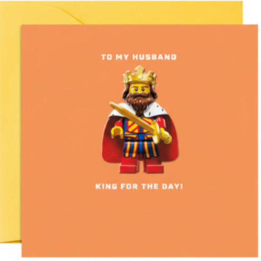 Greeting card with a king-themed design and text 'To my husband, king for the day!' on an orange background.